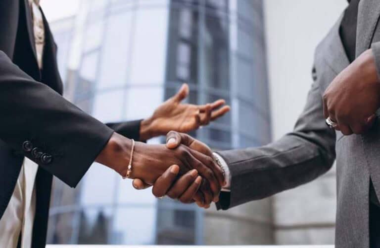 Business professionals shaking hands outside modern office building