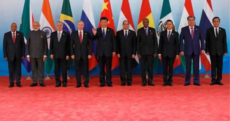World leaders standing before national flags at summit