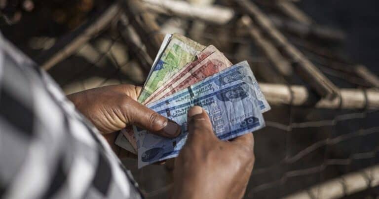 Person counting colorful banknotes near wire fence