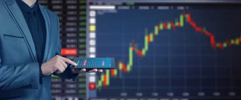 Businessman holding tablet with stock market chart background