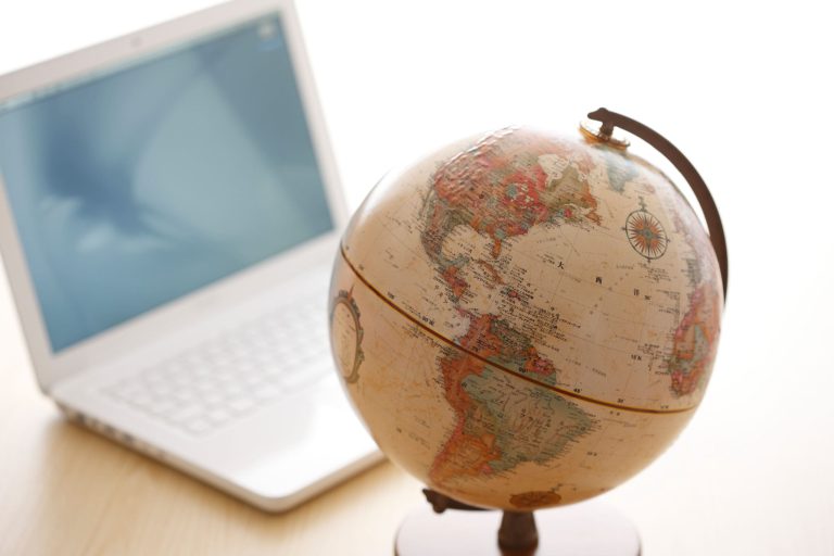 Vintage globe beside open laptop on desk